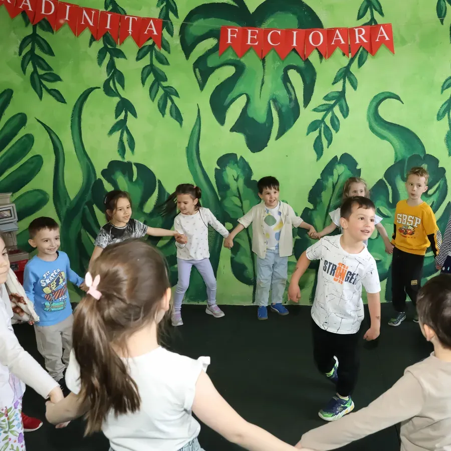 Copii dansând în cerc, ținându-se de mâini