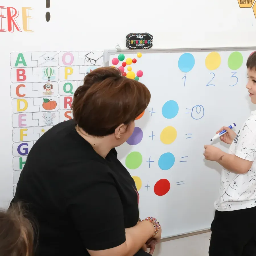 Educatoare la tablă, în fața grupei